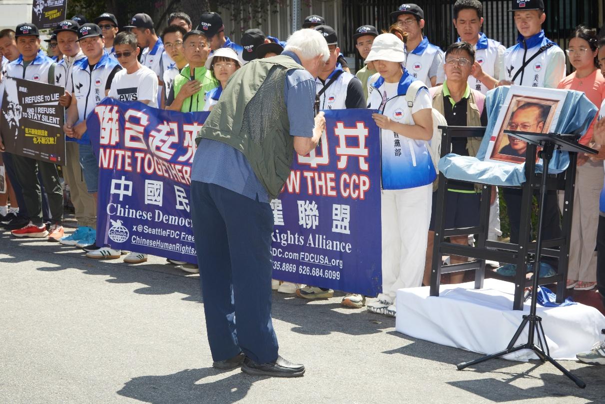 图为:王希哲先生在刘晓波遗像与象征性空椅前深深鞠躬致意,向昔日战友表达沉痛追思